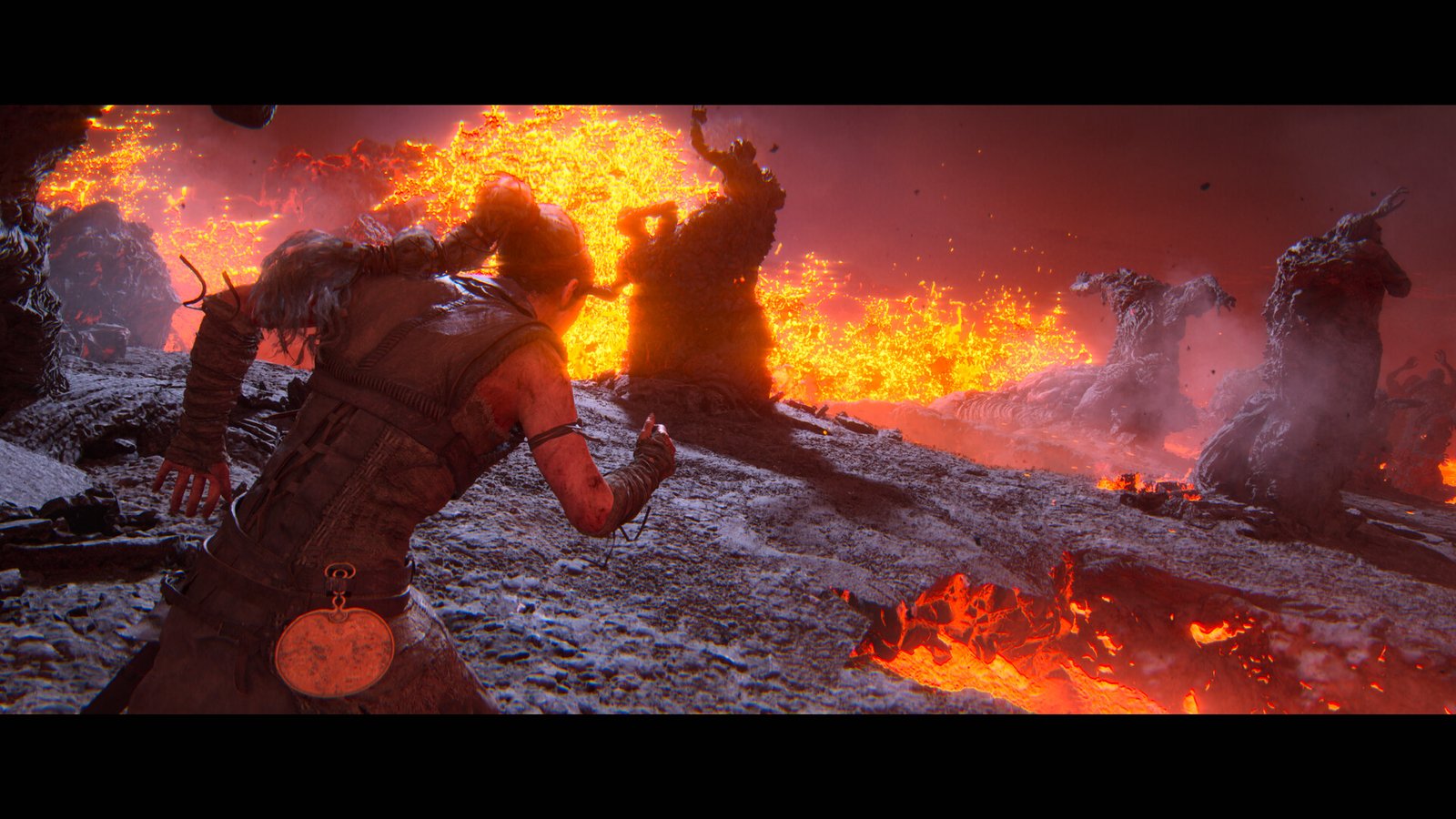 In a volcanic area, with lava flying upwards in front of her, and some lava on the floor next to her, Senua runs between statues of charred people moulded together by the lava. They all have their hands held up